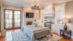 Home Remodeling: Modern kitchen with white cabinetry and elegant decor – A beautifully remodeled kitchen featuring white cabinets, a chandelier, a fireplace, and a dining table with a stylish tablecloth.
